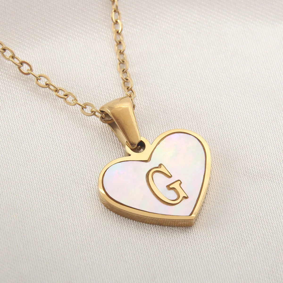 Gold-plated clavicle necklace with a white shell heart pendant, personalised with a letter from A to Z.