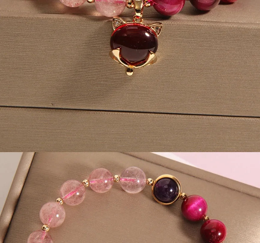 Simple women's bracelet with a red strawberry crystal charm on a black elastic rope.