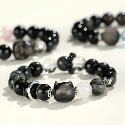 Silver stone crystal bracelet with diamond-shaped fox, cat head, and planet charms on white background.