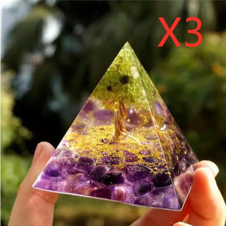 A small 6cm clear epoxy resin pyramid ornament containing pieces of natural crystal gravel on a flat surface.