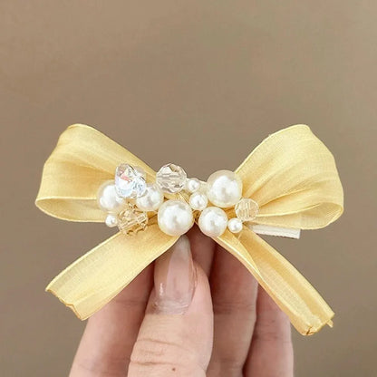 Yellow bow hair barrette clip with rhinestone pearl detail on duckbill clip base