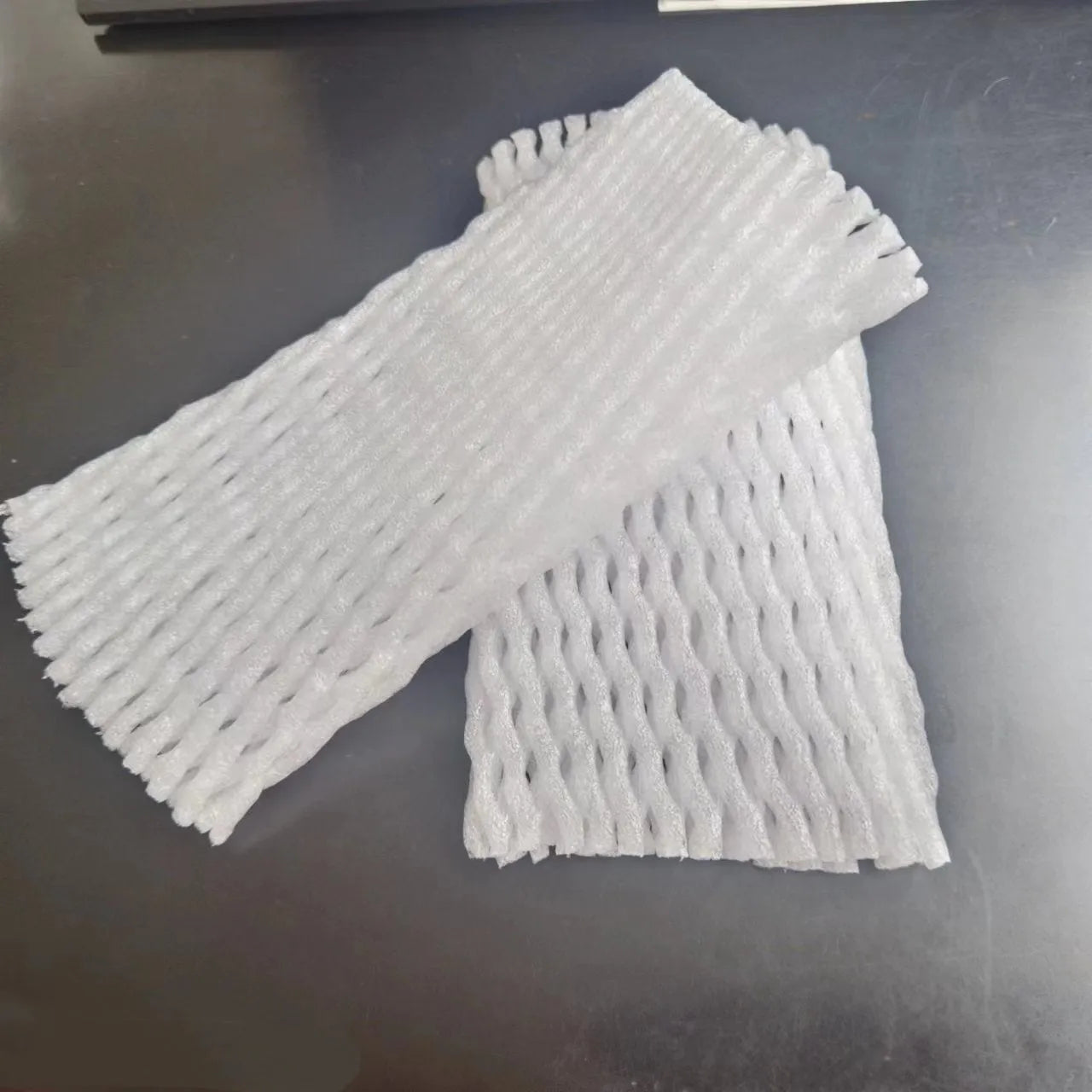A white foam protective net sleeve stretched open, showing its simple tubular construction.