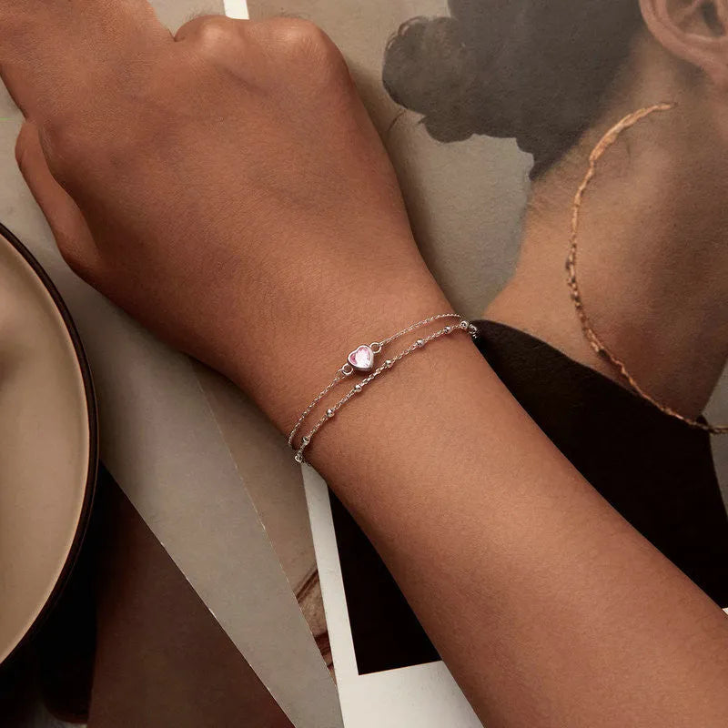 Close-up of a sweet girlish style 925 sterling silver bracelet with a small heart-shaped pendant on an adjustable chain.