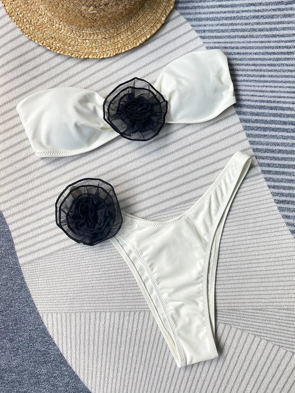 Women's black bikini set with side split bottoms and a white three-dimensional flower detail on the top.
