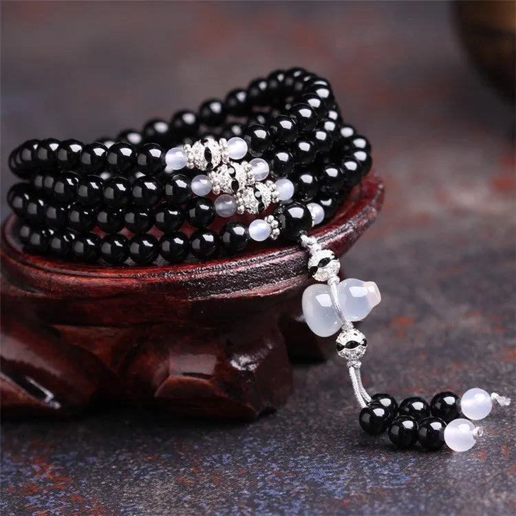 A bracelet made of 108 black geometric agate beads on a wrist.