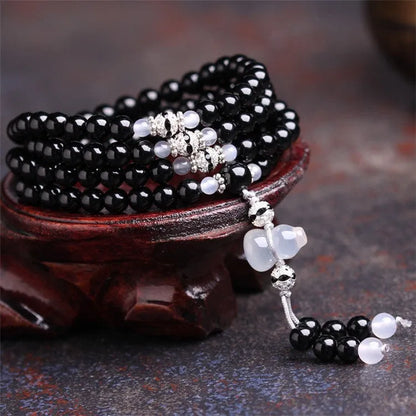 A bracelet made of 108 black geometric agate beads on a wrist.