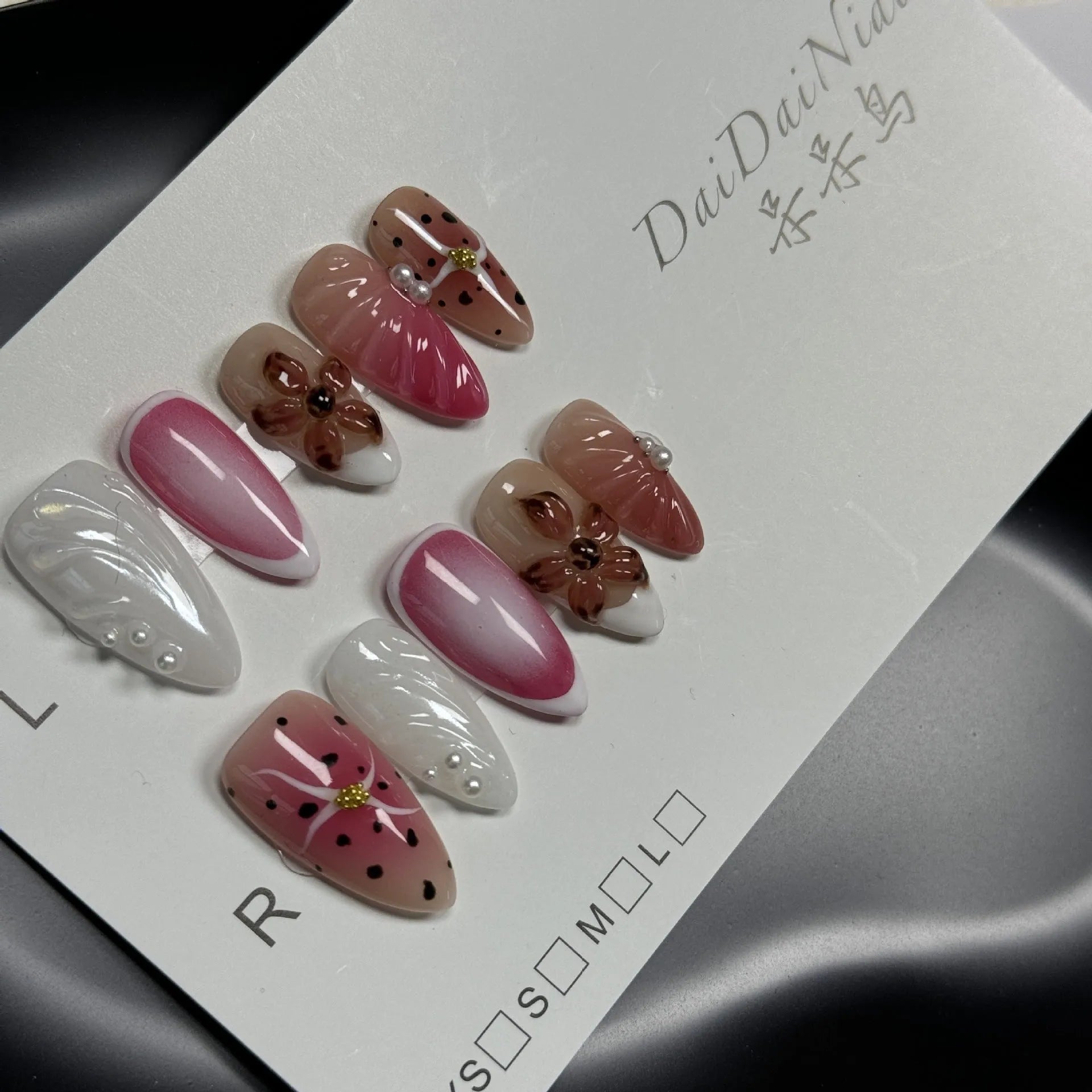Hand-painted 3D embossed candy design nail patches in almond shape on a plastic storage case