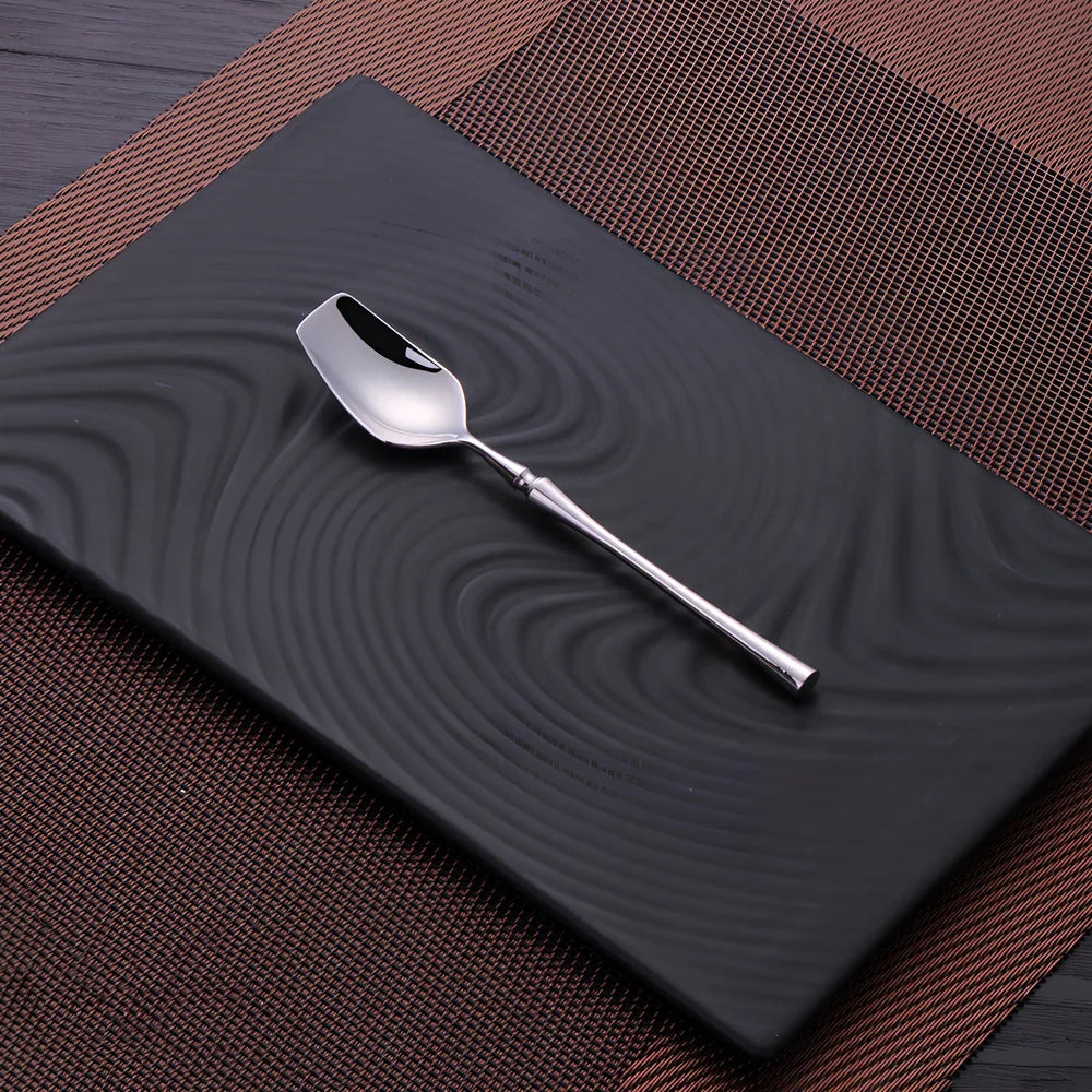 Four-piece stainless steel cutlery set showing main knife, fork, spoon, and teaspoon with mirror finish