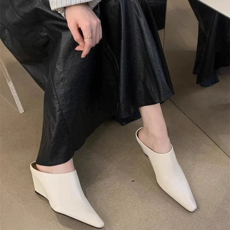Women's black wind wedge closed toe half slippers on a plain background.
