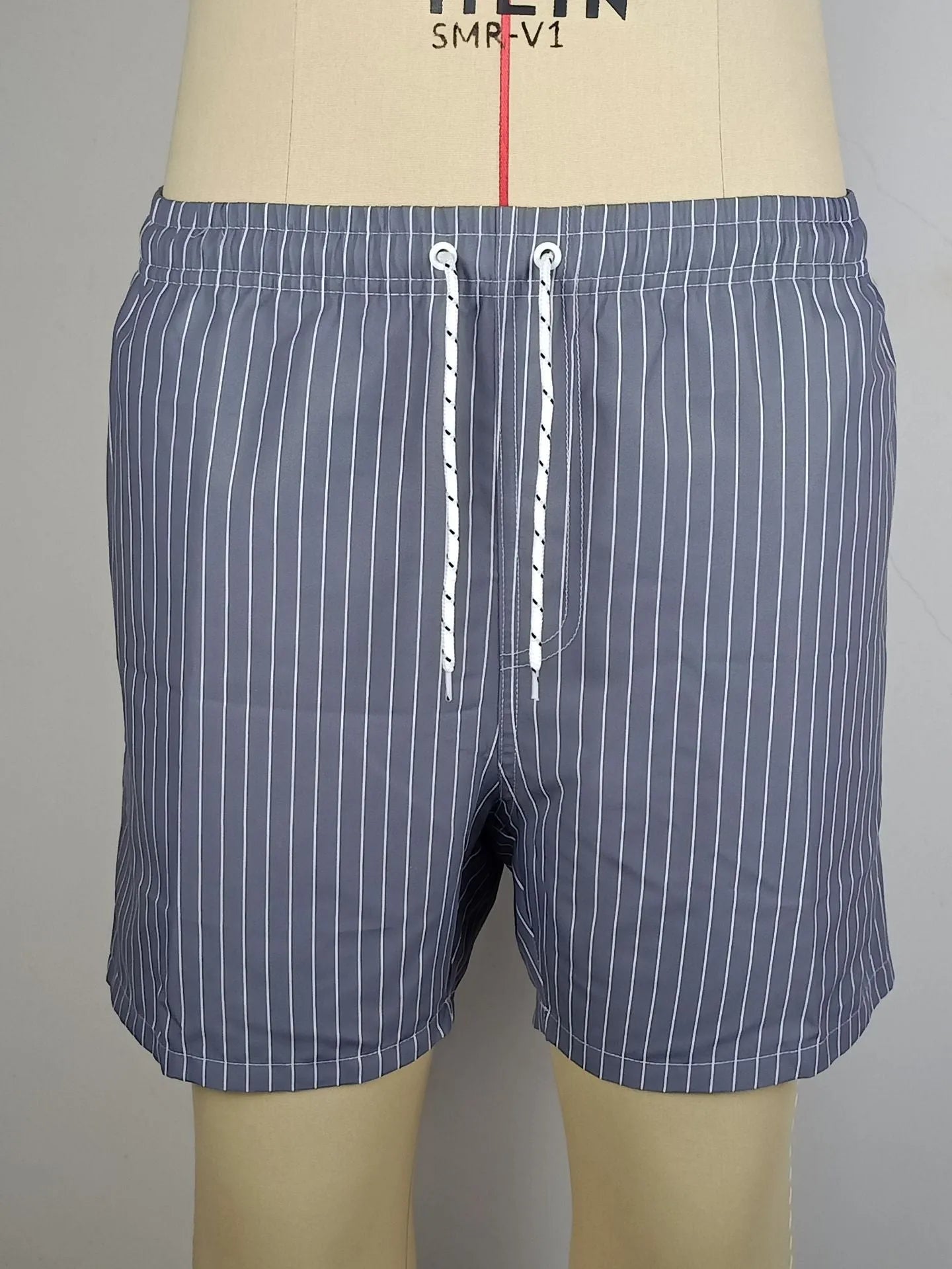 Pair of grey striped polyester shorts with a straight leg cut on a mannequin