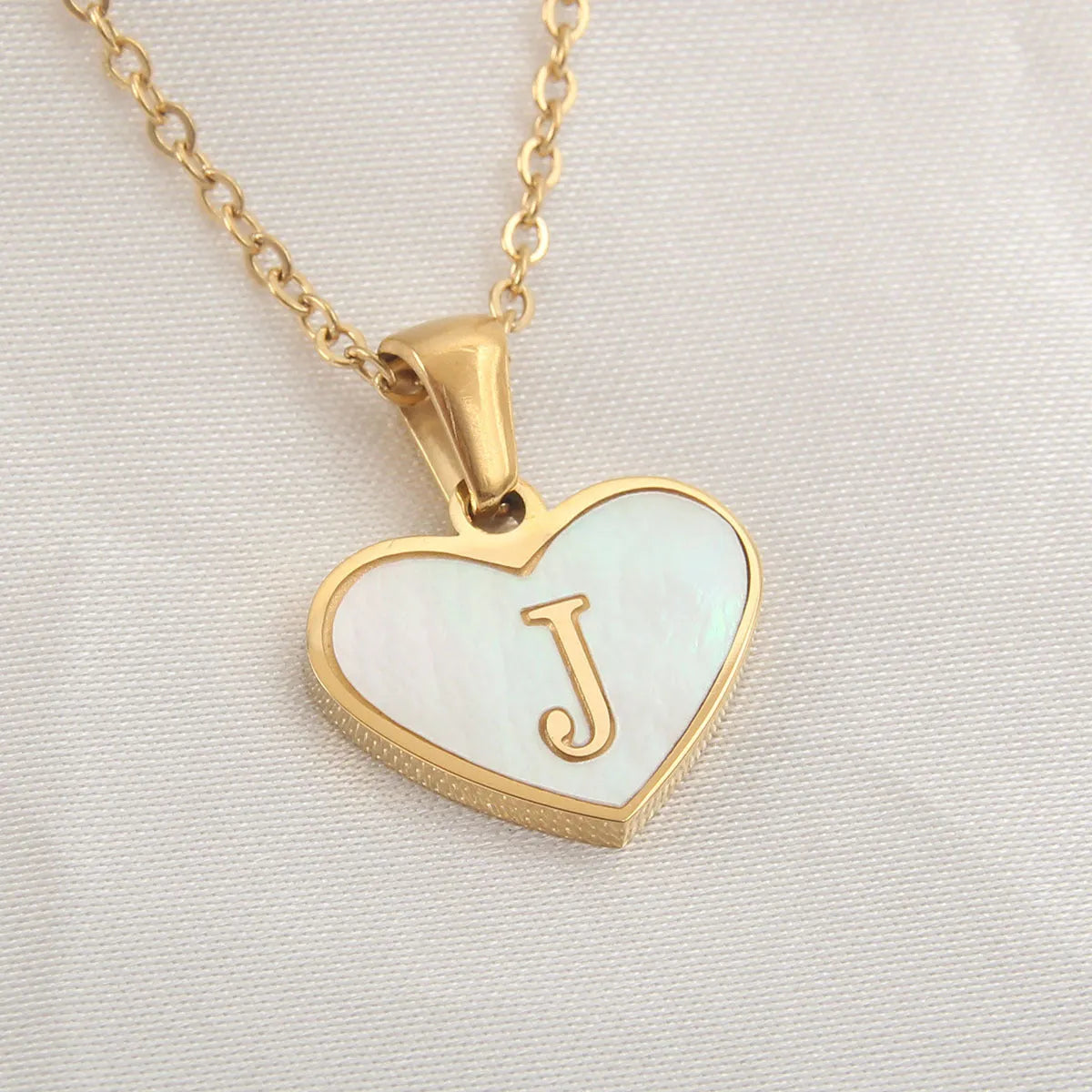Gold-plated clavicle necklace with a white shell heart pendant, personalised with a letter from A to Z.