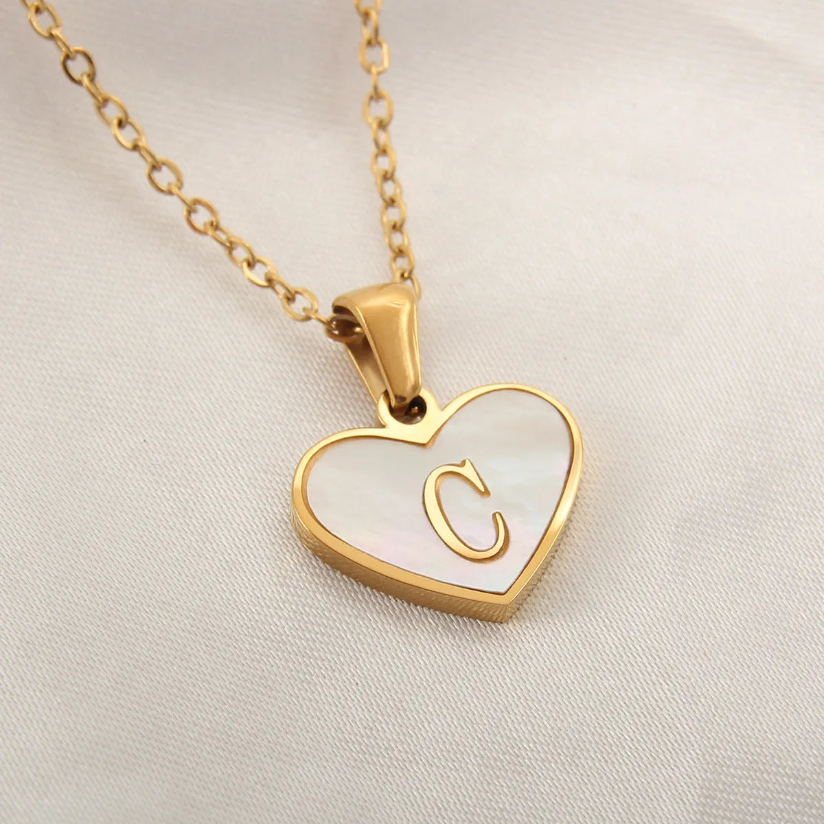 Gold-plated clavicle necklace with a white shell heart pendant, personalised with a letter from A to Z.