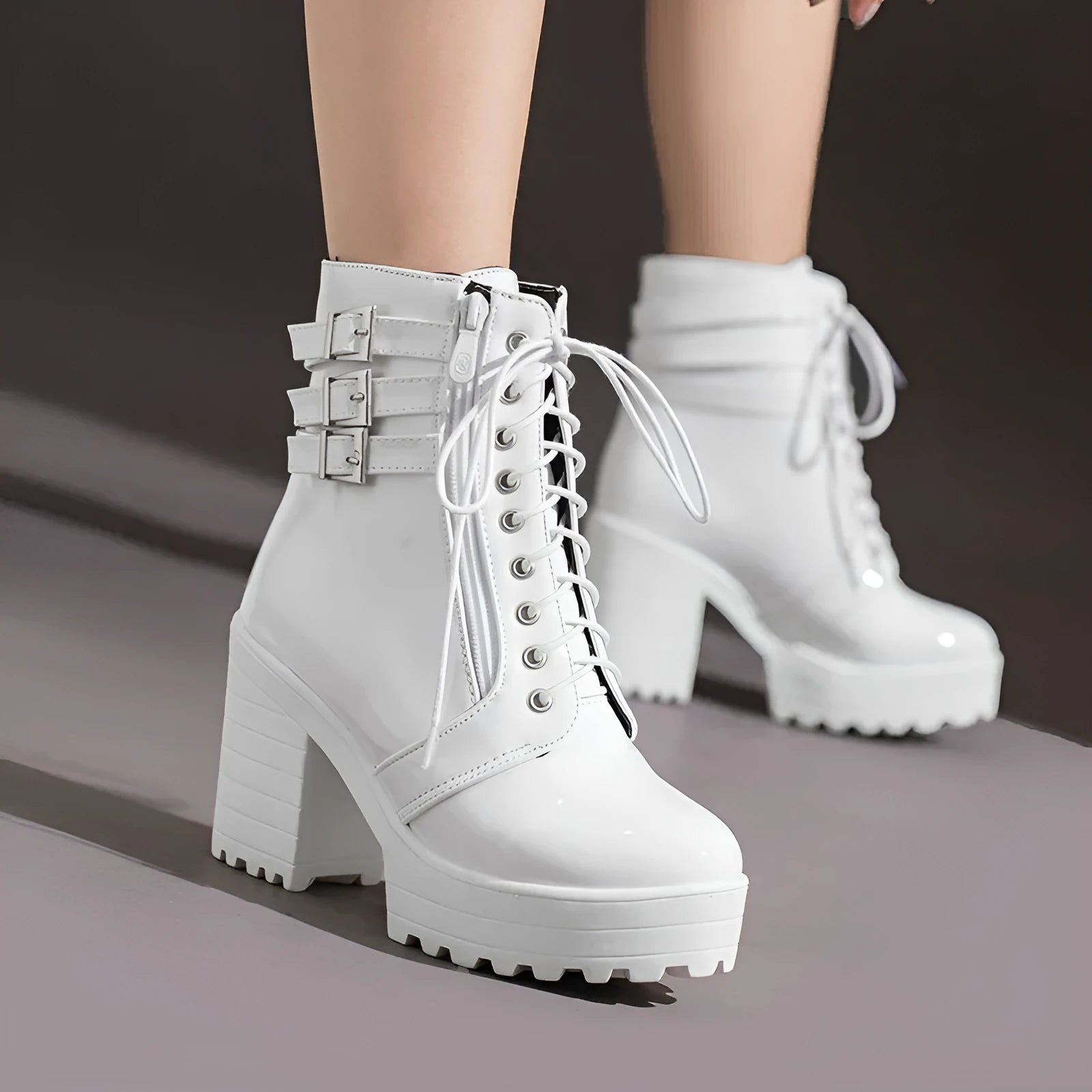 Women's black chunky heel ankle boots with round toe and front lace-up design on a wooden floor.