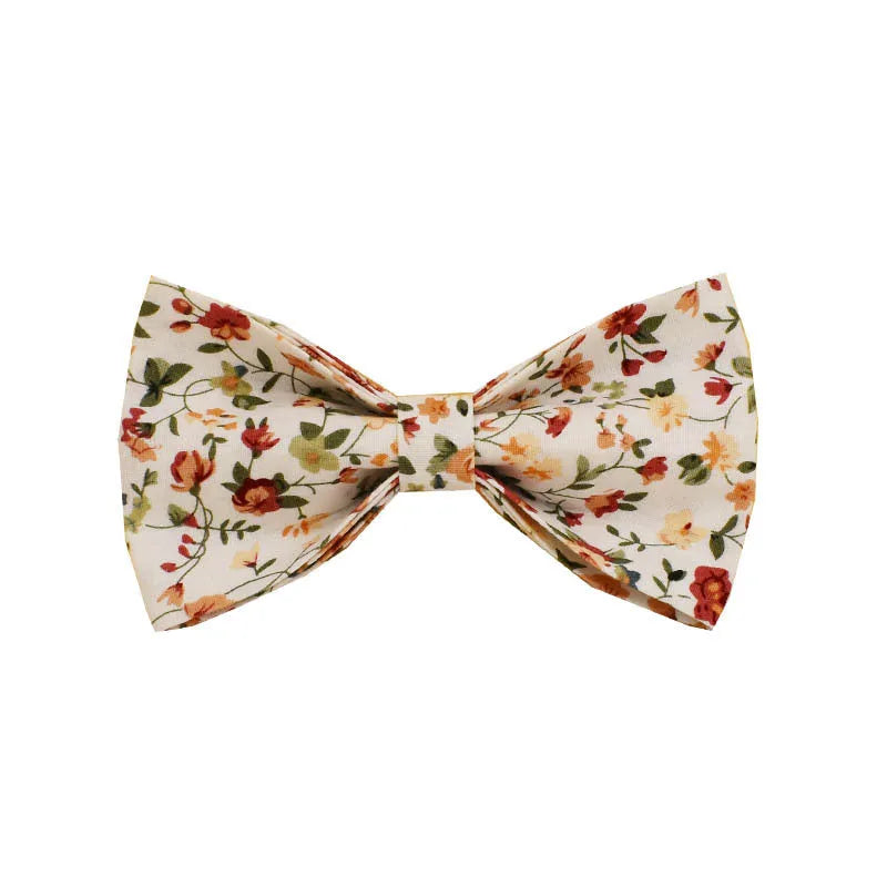Small white flower patterned dog collar, leash, vest, bow, and poop bag holder set laid out flat.