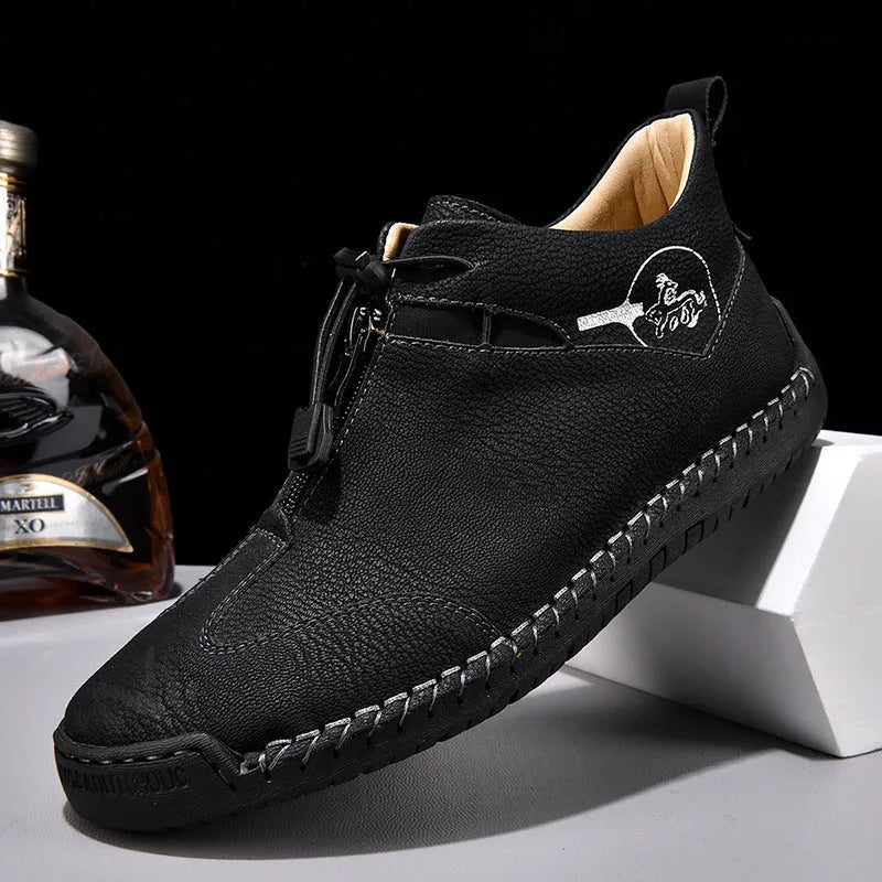 Men's black casual leather shoes with a mid heel, round toe, and visible stitching on a wooden floor.