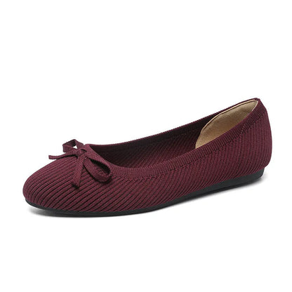 Women's black fabric flat pumps with a bow detail on the round toe, shown on a white background.