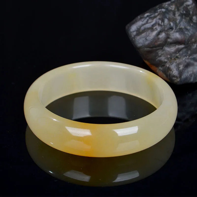 A polished natural light jade bracelet in a traditional Chinese style, shown on a wrist.