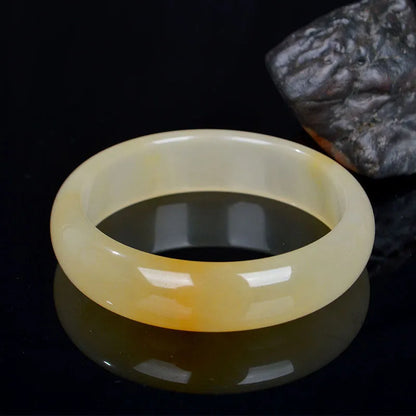A polished natural light jade bracelet in a traditional Chinese style, shown on a wrist.
