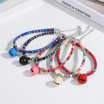 Adjustable coloured ethnic-style pet collar with a small bell, shown in multiple colour options.