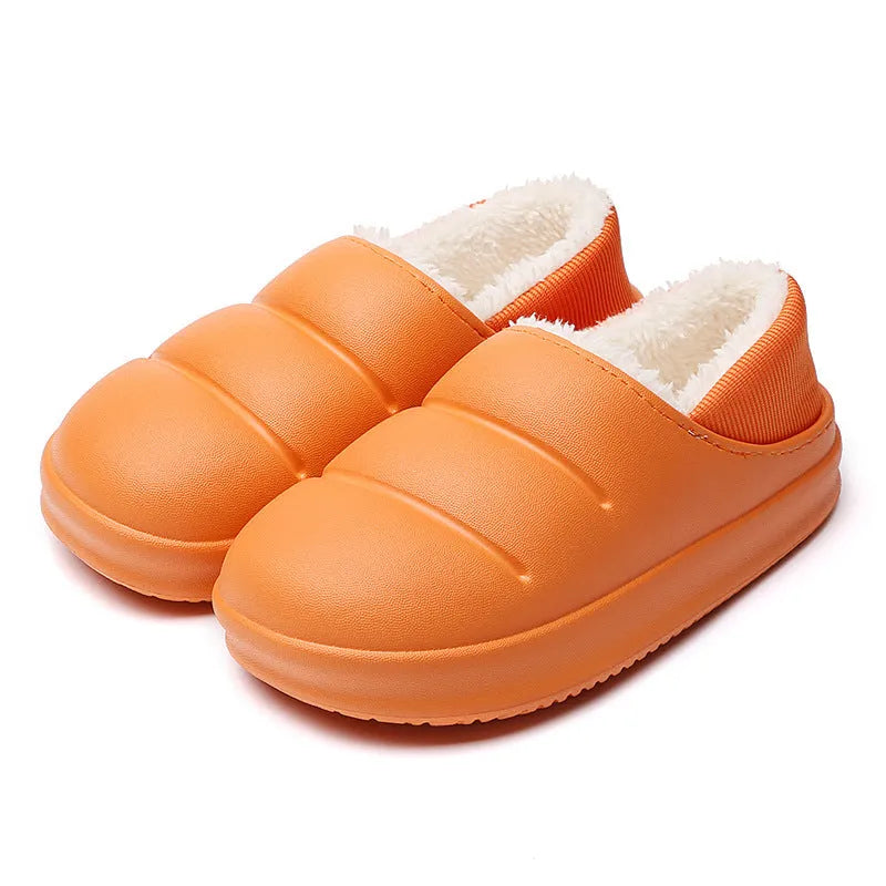 Yellow women's winter slippers with waterproof EVA sole and plush lining on a wooden floor.