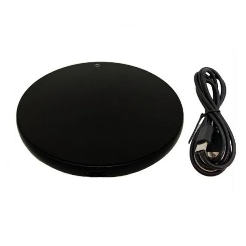 Black USB heating coaster on a desk next to a coffee mug, showing touch controls and coloured indicator light.