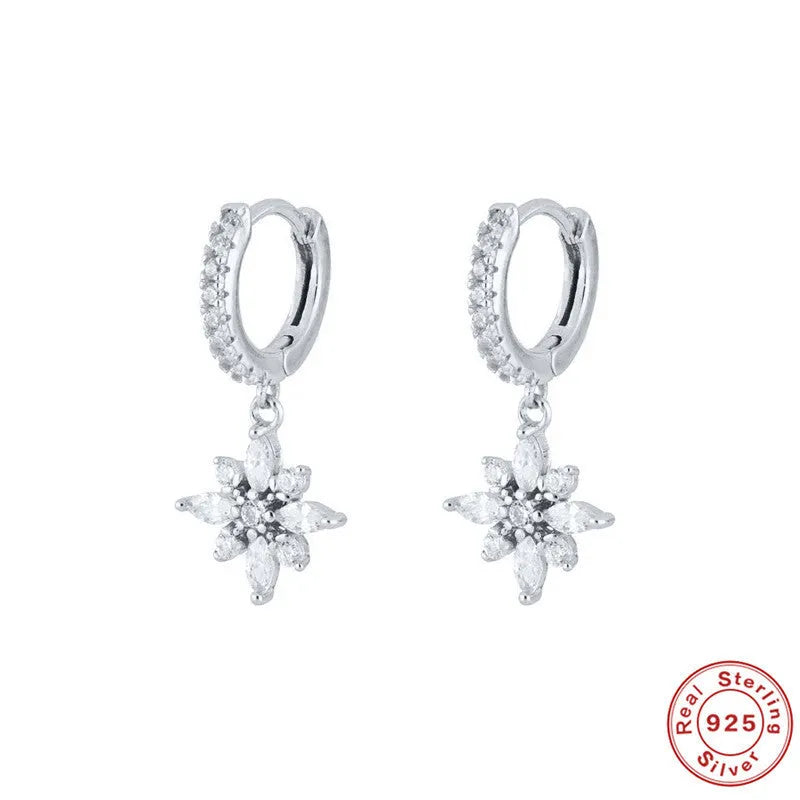A pair of sterling silver snowflake pendant earrings with cubic zirconia stones on a white background.