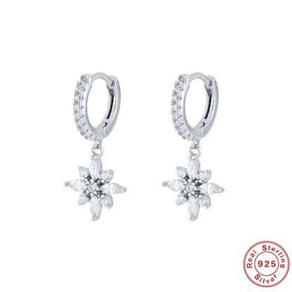 A pair of sterling silver snowflake pendant earrings with cubic zirconia stones on a white background.
