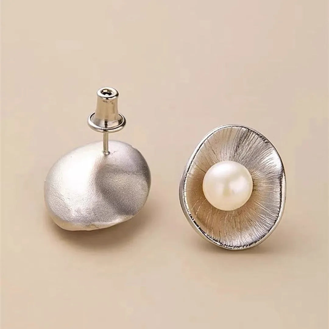 A pair of gold-coloured geometric sterling silver stud earrings with white pearl accents on a white background.
