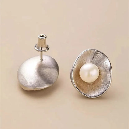 A pair of gold-coloured geometric sterling silver stud earrings with white pearl accents on a white background.
