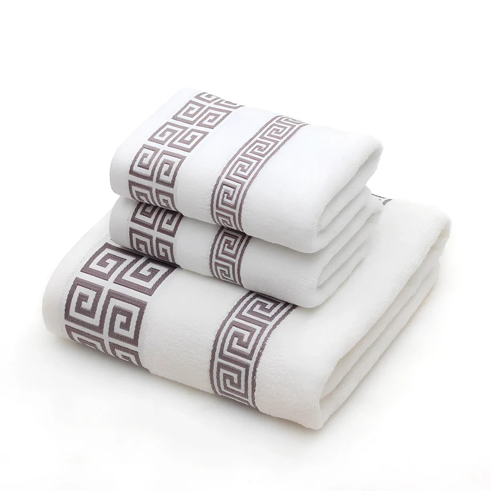 Three-piece cotton towel set showing 70cm bath towel and two 34cm hand towels in white, dark blue, and brown colours
