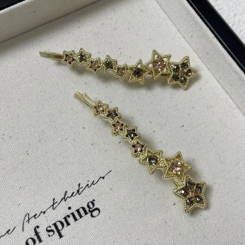 Gold electroplated hair barrette with a rhinestone five-pointed star, broken clip style for bangs.