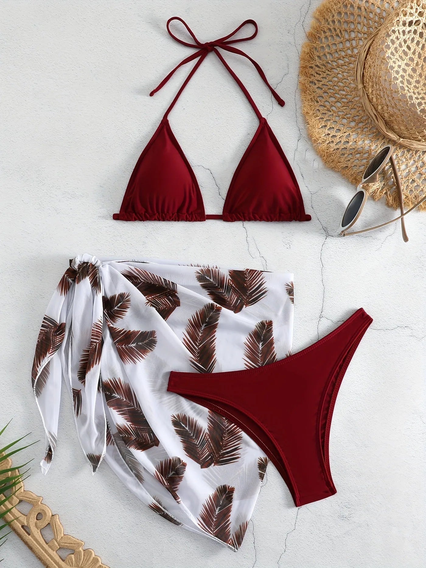 Women's orange three-piece bikini swimsuit with a matching printed gauze skirt laid flat.