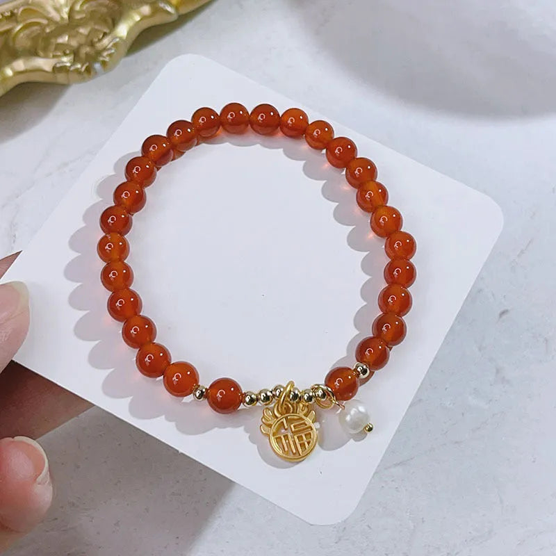 Close-up of a red agate bracelet featuring a detailed dragon design in a Chinese style.