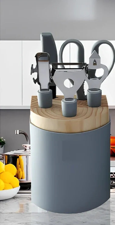 Stainless steel kitchen utensil set with whisk, grater, peeler, scissors and other tools on grey background