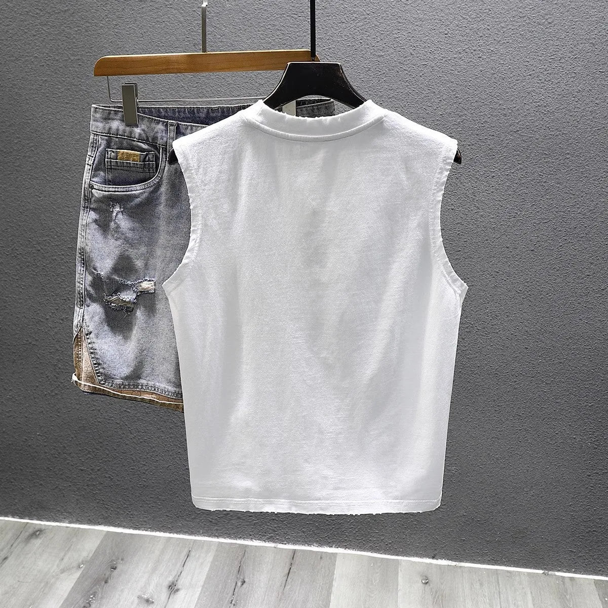 Men's solid colour loose fit cotton sleeveless t-shirt on a hanger, shown in white and black.