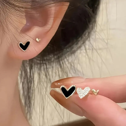 Three pairs of heart-shaped electroplated earrings in gold, black, black and white, and pink colours