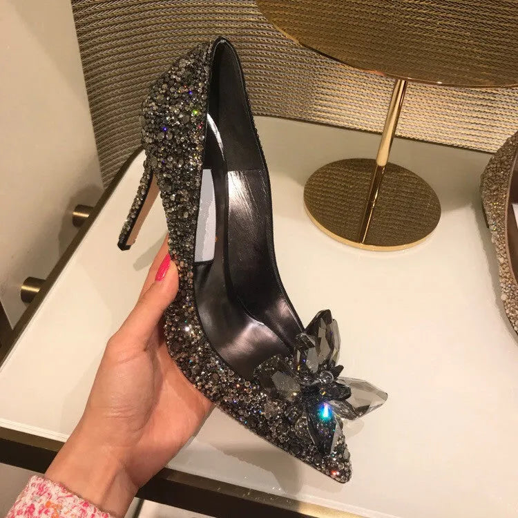 Women's gold pointed toe high heels with rhinestones and stiletto heel on a light background