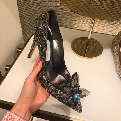 Women's gold pointed toe high heels with rhinestones and stiletto heel on a light background