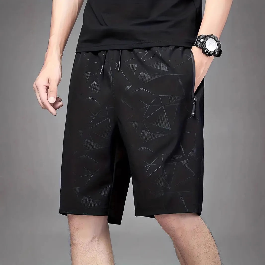 Men's loose-fit casual sports shorts in grey with a printed pattern, showing elastic waistband and fifth-pants length.