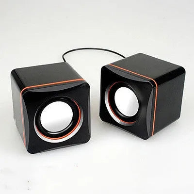 Black square USB computer speaker measuring 10cm with matte finish beside monitor