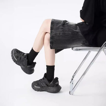 Man wearing loose fit black ripped denim shorts with distressed detailing and a washed vintage finish.