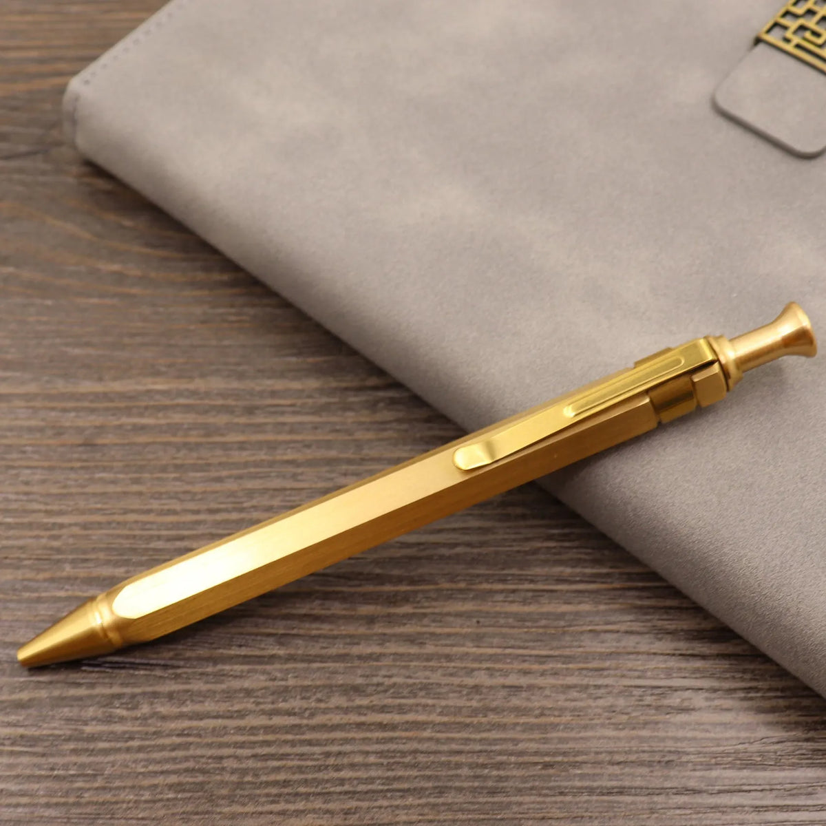 Brass tactical pen with press bolt mechanism showing cylindrical design and six ring details