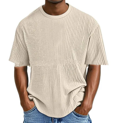 Man wearing a light blue waffle-textured cotton blend short sleeve t-shirt, casual pullover style.
