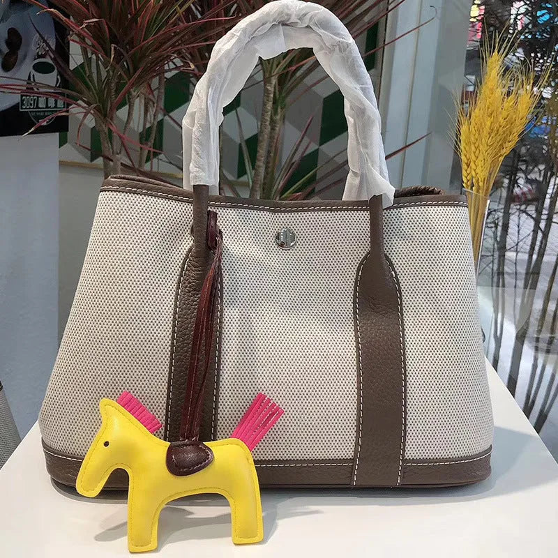 Genuine leather and canvas women's tote bucket bag in black, shown with a soft carry handle.