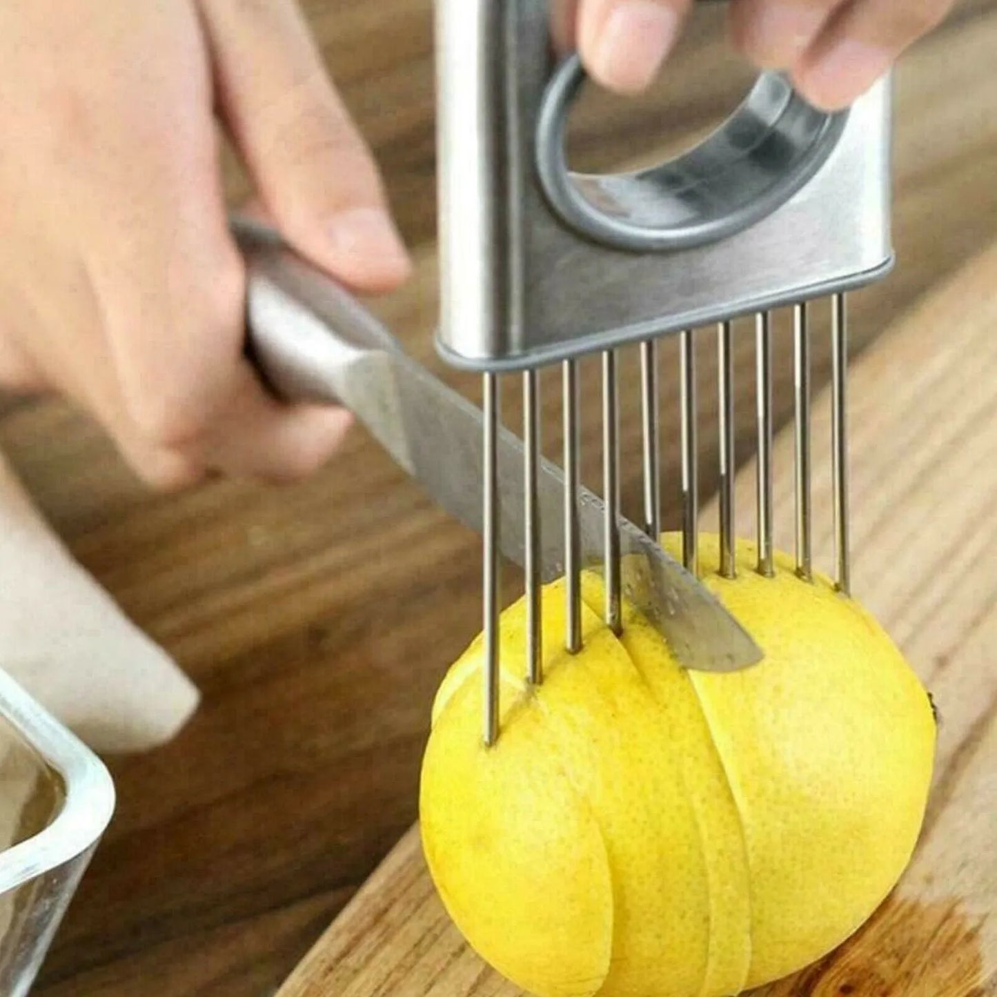 Stainless steel onion holder slicer tool with sharp prongs and a finger guard protector on a kitchen surface.