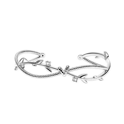 Close-up of a white gold coloured twisted copper bracelet with a branch and sprout design.