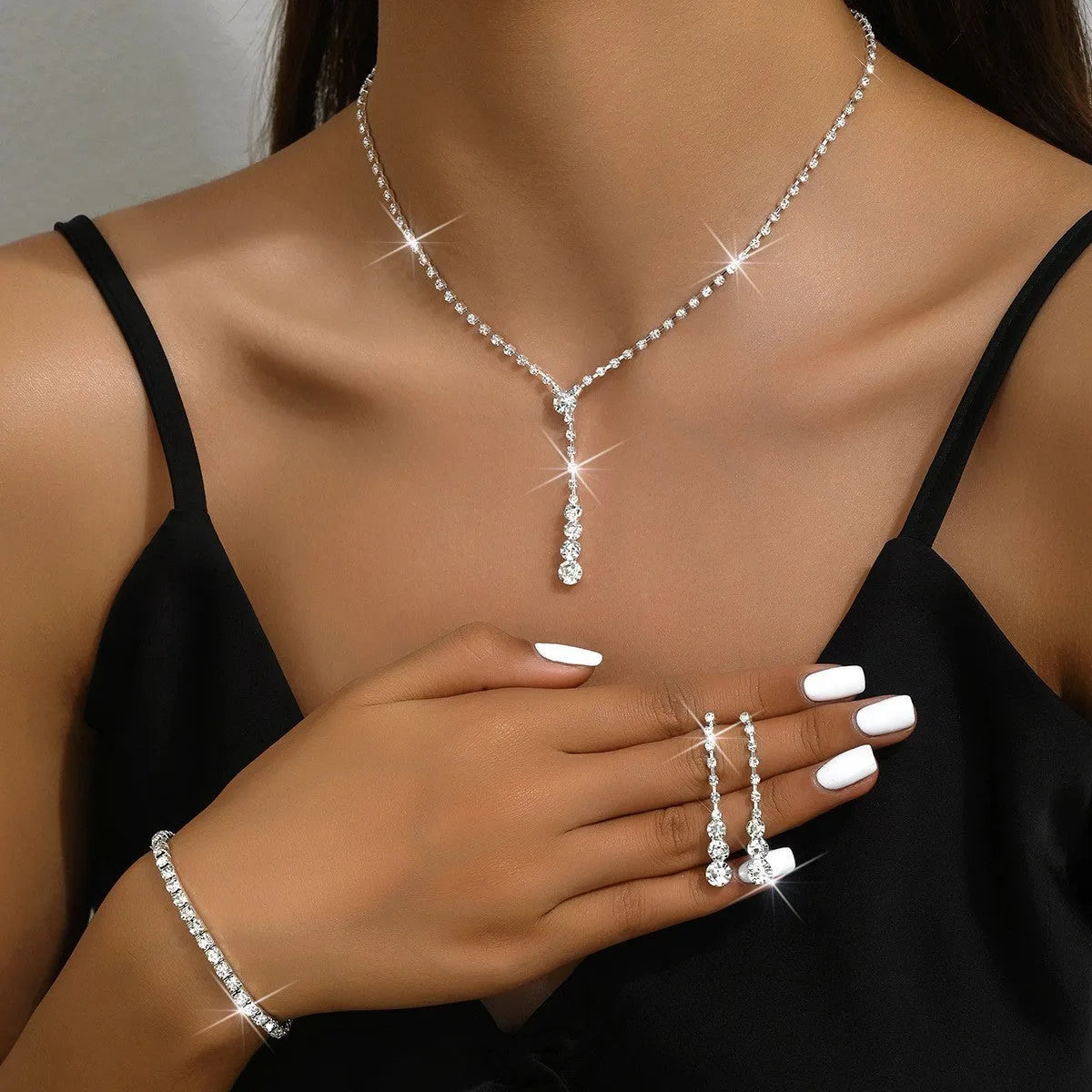 Women's silver pink rhinestone heart tassel earrings, necklace, and bracelet jewellery set on a white background.
