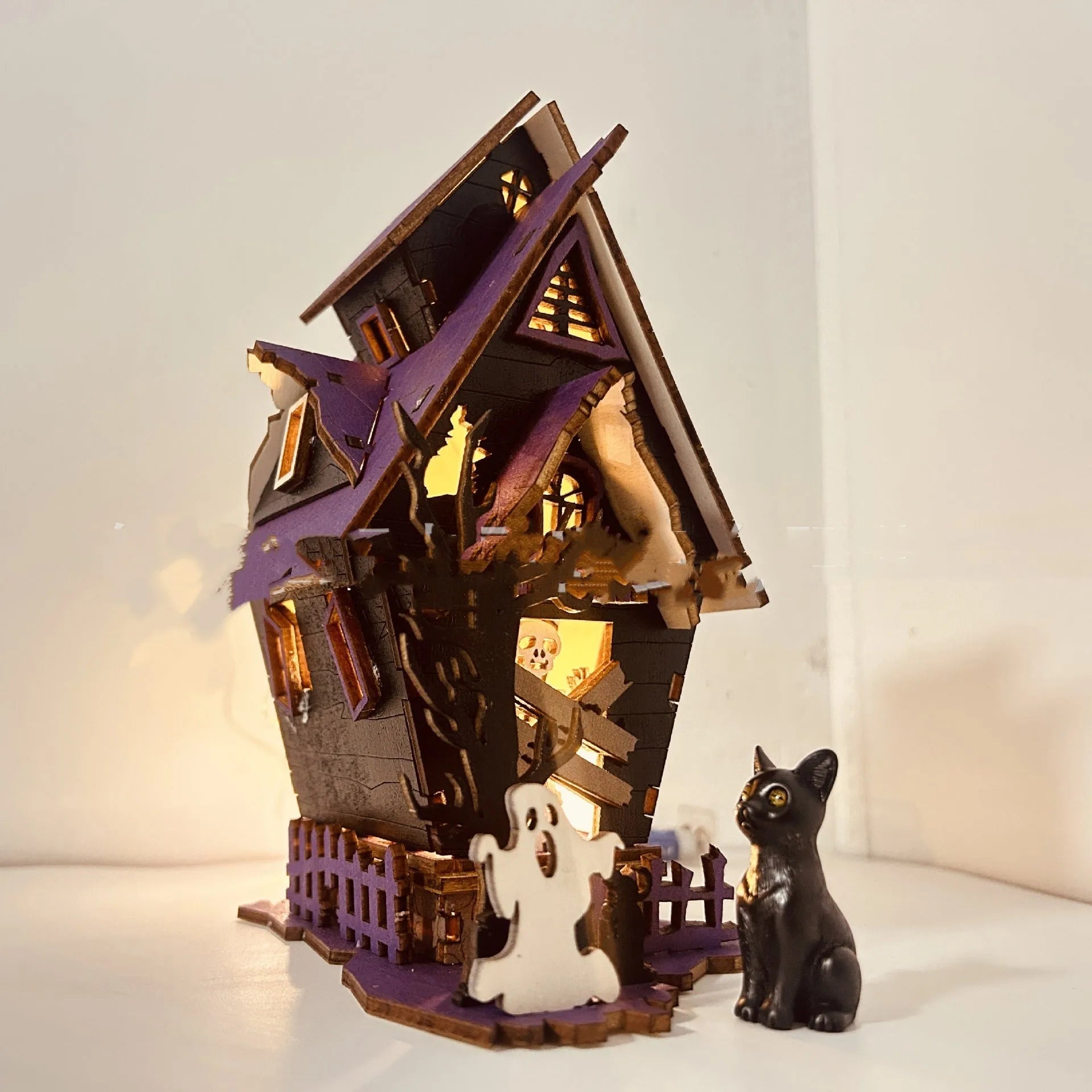 Wooden haunted house table decoration measuring 14x10.5x19cm with luminous finish and candlestick holder function