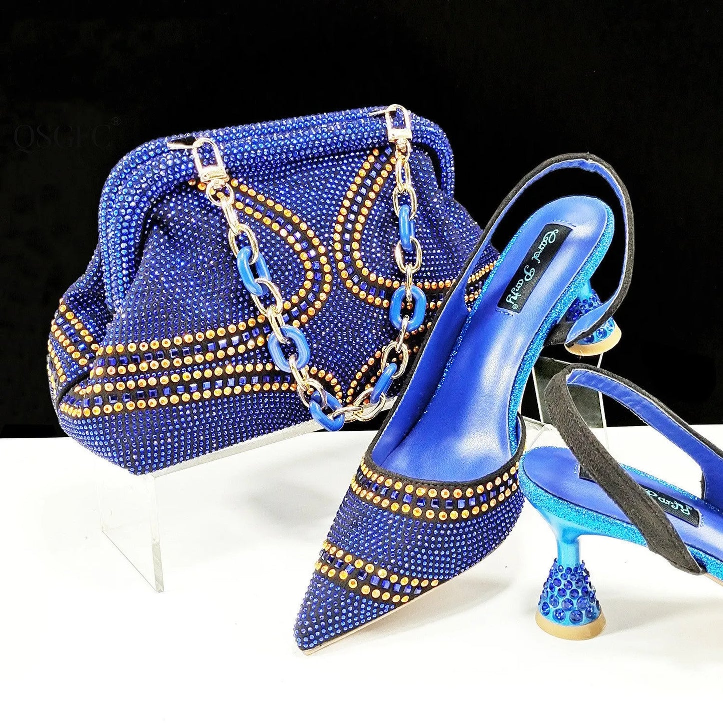 Women's pointed toe high heel court shoes in blue with rhinestone detail and a matching small bag.