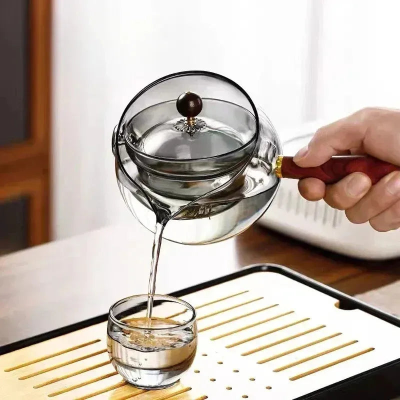 Glass teapot with wooden handle showing transparent borosilicate construction and removable infuser